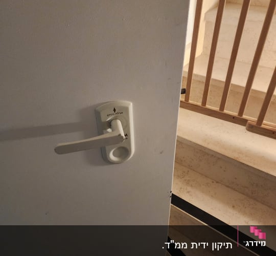ידית דלת לבנה עם מנעול על דלת פתוחה